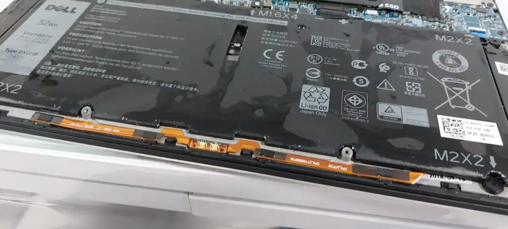 שלוליות מים על סוללה פנימית של מחשב נייד Dell לאחר חדירת נוזלים למחשב